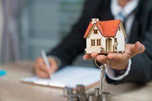 man with house on his hand and set of keys